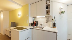 Une cuisine moderne avec des meubles blancs, un mur d’accent jaune et une machine à café intégrée.