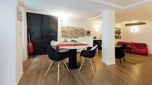 Un salon moderne avec un coin repas, comprenant un mur en pierre, un canapé rouge et une table à manger avec des chaises.