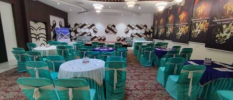 A conference room with round tables, green chairs, and floral carpet.