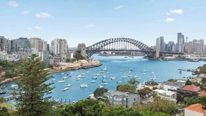 Een uitzicht op de Harbour Bridge van Sydney met tal van boten op het water, omringd door stadsgebouwen en groen.
