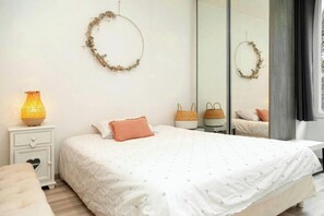 Ein Schlafzimmer mit einem Bett, einem Nachttisch mit Lampe, einem Spiegel und zwei Körben.