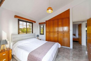 A bedroom with a large bed, wooden wardrobe, and a window with a view. - Villa Adonis Large Private Pool, Walk to Beach (Argaka)