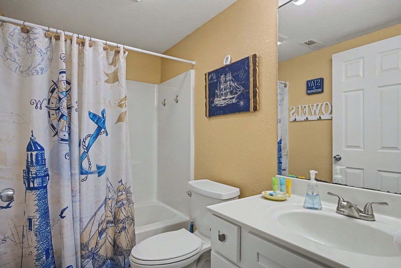 A bathroom with a white bathtub, a toilet, and a sink with toiletries.