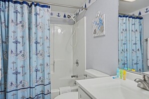 Een badkamer met een douche, wastafel en spiegel.