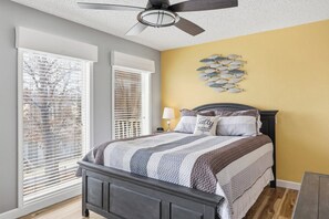 A bedroom with a bed, a ceiling fan, a wall clock, and a decorative fish wall art piece. - Southwood Shores 217-1A (Village of Four Seasons)