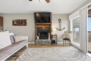 A living room with a fireplace, a sofa, a patterned rug, and a view of the outdoors. - Southwood Shores 217-1A (Village of Four Seasons)