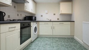 A compact kitchen with white cabinets, a built-in oven, a washing machine, and a microwave. - Modern 2-bed Apartment Near Wembley Stadium (Wembley)