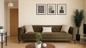 A living room with a sofa, a coffee table, and framed artwork on the wall. - Modern 2-bed Apartment Near Wembley Stadium (Wembley)