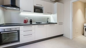 A modern kitchen with white cabinets, a built-in microwave, a stainless steel range hood, and a built-in oven. - Palazzo Accademia-Beato Angelico-2 (Firenze)