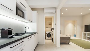A modern kitchen with a built-in microwave, a coffee machine, and a washing machine in the adjacent room. - Palazzo Accademia-Beato Angelico-2 (Firenze)