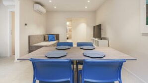 A modern dining area with a wooden table, blue chairs, and a sofa with cushions. - Palazzo Accademia-Beato Angelico-2 (Firenze)