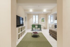 Una sala de estar moderna con un televisor de pantalla plana, sillas verdes, una mesa de comedor y un sofá.