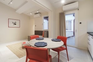Een moderne eetruimte met een ronde tafel, rode stoelen en een vloer in een lichte kleur.