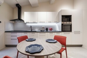 Een moderne keuken met witte kasten, een zwarte afzuigkap en een ingebouwde magnetron.