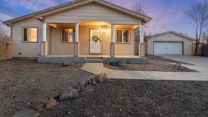 Et etplanshus med en veranda, garage og en velplejet græsplæne.