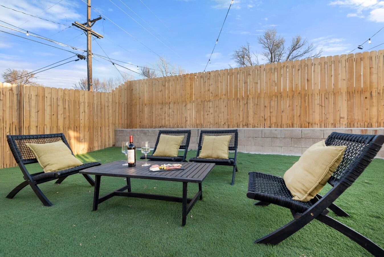 An outdoor patio with a wooden fence, a table, and four chairs.