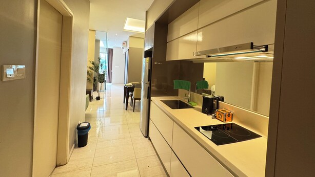 A modern kitchen with a built-in stove, a sink, and a dining area with a table and chairs. - Dorsett Hartamas|KL City|Rooftop Pool|Bathtub|1KM from 1Mont Kiara|8KM from KLCC (Kuala Lumpur)