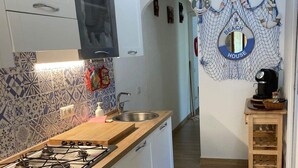 A modern kitchen with a gas stove, white cabinets, and patterned backsplash. - Cozy house with garden on two sides 350m from the sea (Costa Rei)