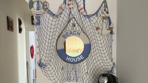 A hallway with a wall-mounted decorative net featuring a circular sign that reads "BEACH HOUSE". - Cozy house with garden on two sides 350m from the sea (Costa Rei)
