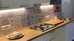 A kitchen with white cabinets, a patterned backsplash, a gas stove, and a sink. - Cozy house with garden on two sides 350m from the sea (Costa Rei)
