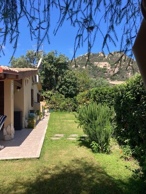A house with a tiled patio, a small garden, and a view of a mountain.