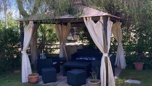 A covered outdoor seating area with cushioned furniture and potted plants. - Cozy house with garden on two sides 350m from the sea (Costa Rei)