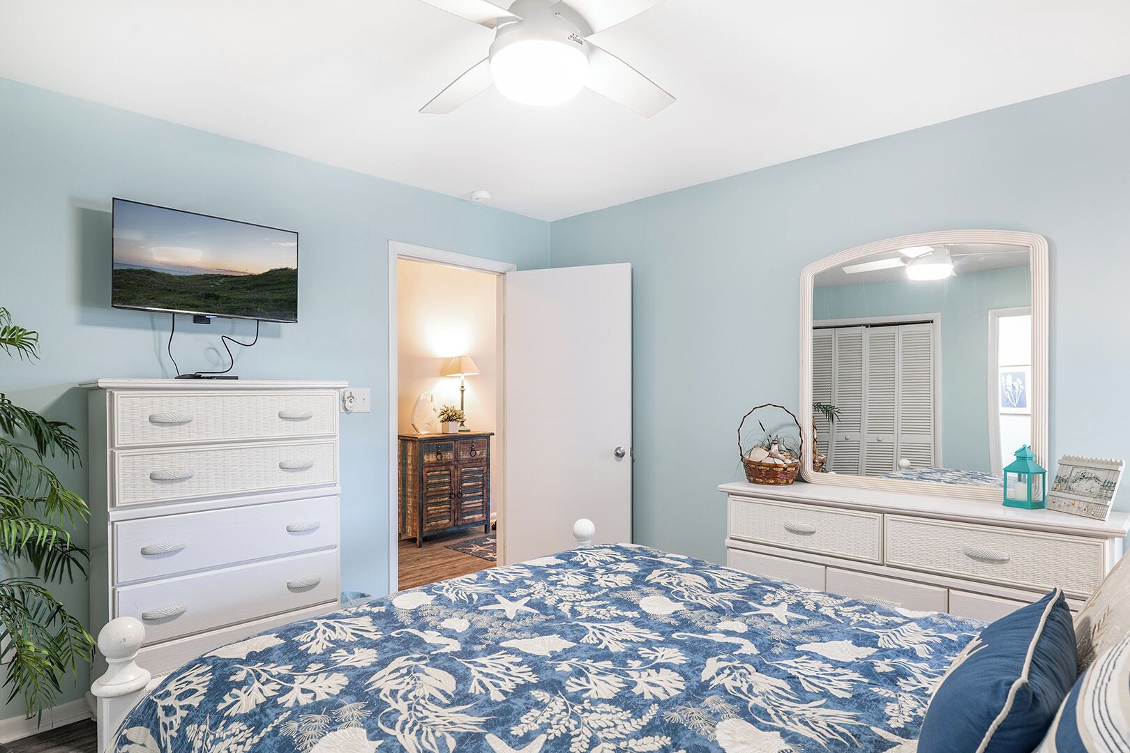 Un dormitorio con cama, cómoda y televisor montado en la pared.