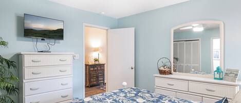 Un dormitorio con cama, cómoda y televisor montado en la pared.