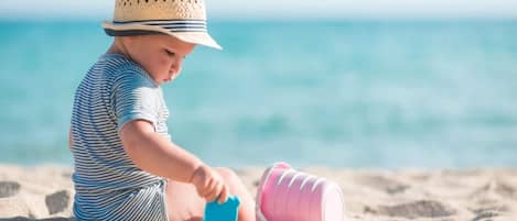 Een kind speelt met zandvormpjes op het strand.