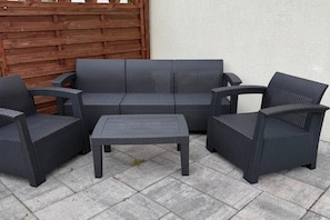 A patio furniture set consisting of a sofa, two armchairs, and a coffee table.