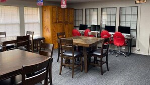 Una sala de conferencias con una mesa y sillas de madera, un mueble de madera grande y múltiples monitores de computadora.
