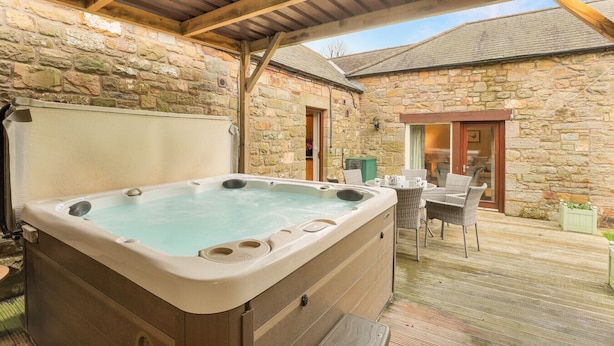 Ein Steinhaus mit Whirlpool, Sitzgelegenheit im Freien und Holzboden.
