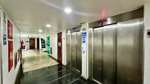 A hotel corridor with elevators, a fire extinguisher, and a sign indicating a social area. - Loft equipado a poucos passos da praia (Arraial do Cabo)