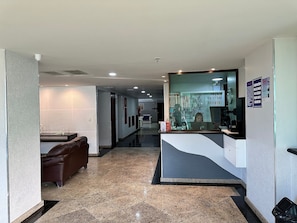 A hotel reception area with a counter, seating, and a visible corridor. - Loft equipado a poucos passos da praia (Arraial do Cabo)