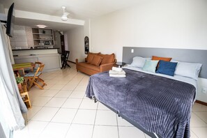 Ein Schlafzimmer mit Bett, einer Couch, einem Esstisch mit Stühlen, einer Küchenzeile und einem Deckenventilator.