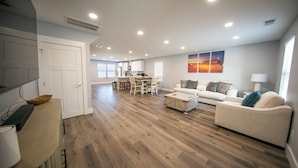 A spacious living area with a dining table, sofa, and a kitchen in the background. - Stadium, mall,civic center, dining, shopping (Knoxville)