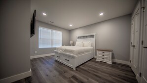 A bedroom with a bed, nightstands, a dresser, and a window with blinds. - Stadium, mall,civic center, dining, shopping (Knoxville)