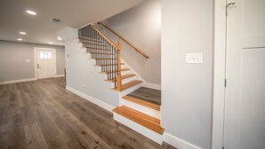 A spacious room with a wooden staircase, white walls, and a door. - Stadium, mall,civic center, dining, shopping (Knoxville)