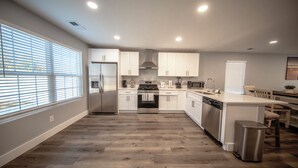 A modern kitchen with white cabinets, stainless steel appliances, and a wooden floor. - Stadium, mall,civic center, dining, shopping (Knoxville)
