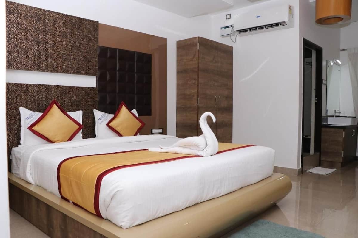 Una habitación de hotel moderna con una cama grande, un cabecero con diseño texturizado y un armario de madera.