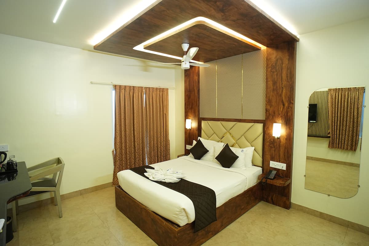 Habitación de hotel con una cama grande, un escritorio con silla, un ventilador de techo y un espejo en la pared.