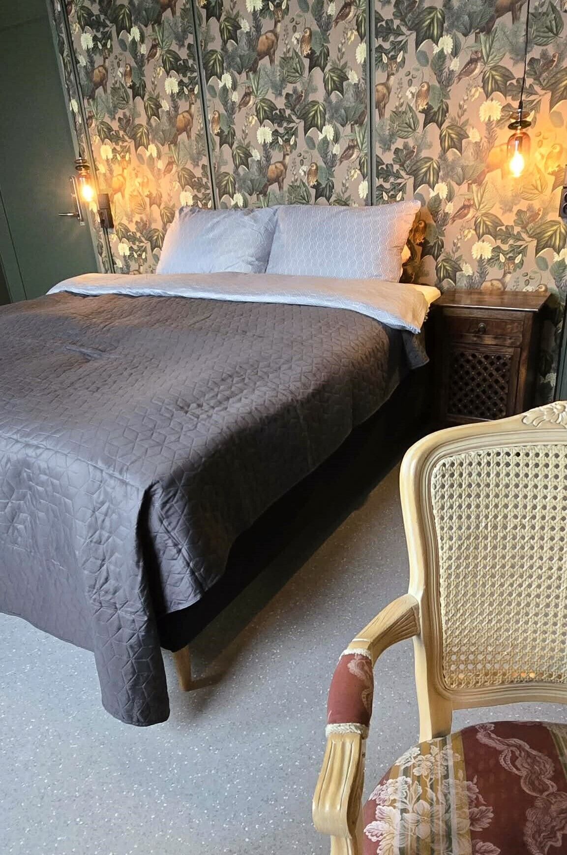 Un dormitorio con una cama, una mesita de noche y una silla.