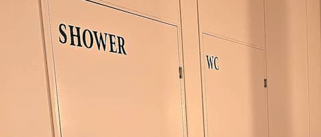 A row of beige doors with labels 'SHOWER' and 'WC' indicating a bathroom area.