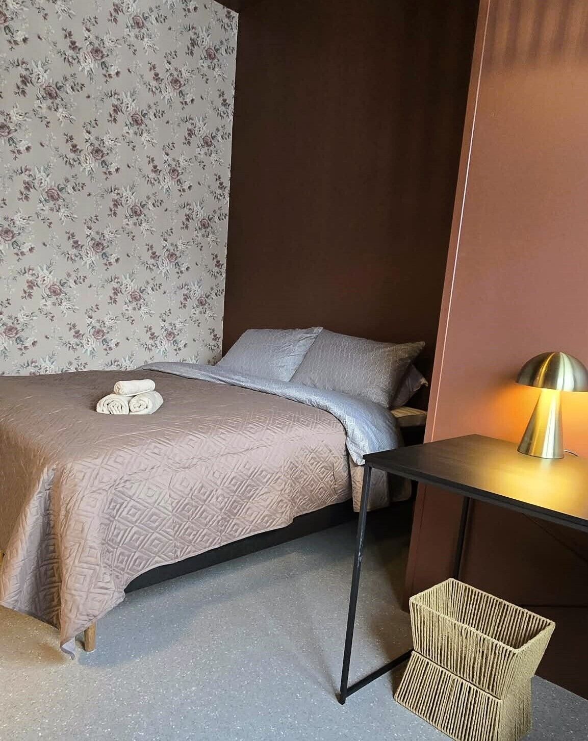Un dormitorio con una cama, una mesita de noche con lámpara y una silla.
