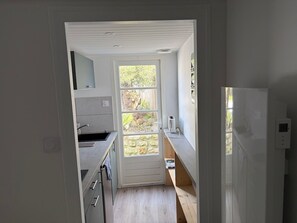 A narrow kitchen with a window, a built-in oven, and a small countertop. - La Cotinière - House with swimming pool, facing the beach (Saint-Pierre-d'Oléron)