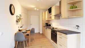 Eine moderne Küche mit Holzschränken, einem Einbauofen und einem Essbereich mit Tisch und Stühlen.