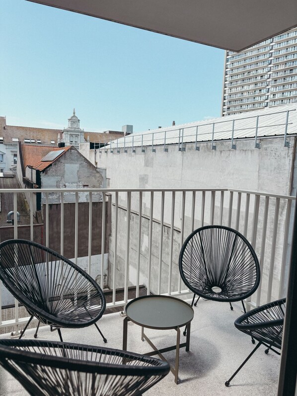 A balcony with four black wire-framed chairs and a small round table. - Luxury apartment in the heart of Ostend (Oostende)