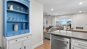 Uma cozinha moderna com armário azul, eletrodomésticos de aço inoxidável e vista para a sala de estar.