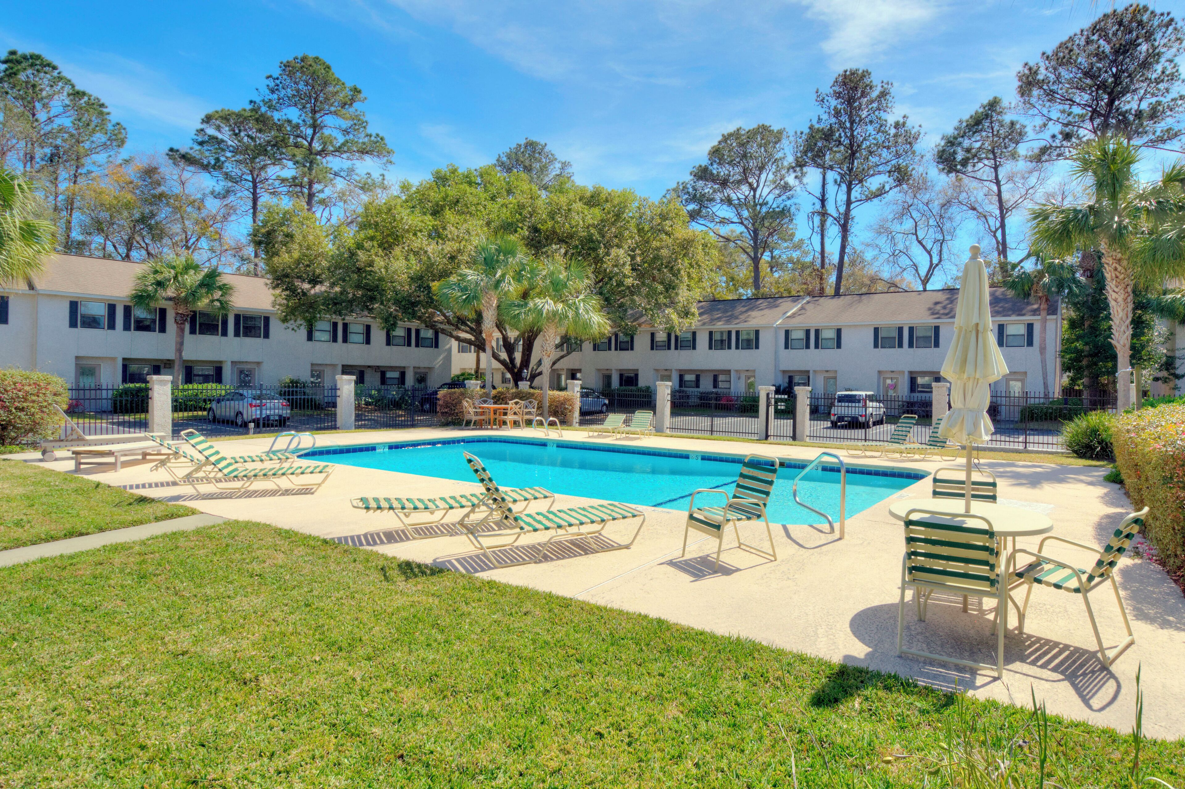 A pool area with lounge chairs and a building in the background.