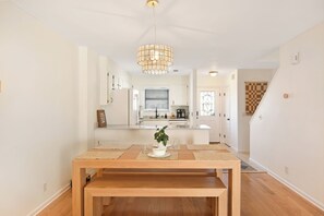 Una cocina moderna con armarios blancos, una isla central y una lámpara colgante.